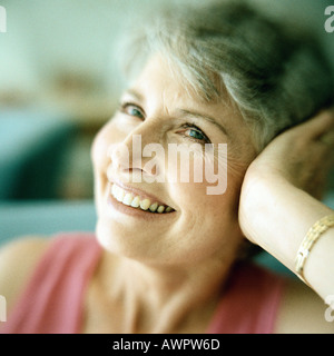 Portrait of mature woman smiling with head resting in hand Stock Photo