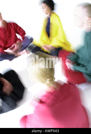People sitting on floor in lotus position, meditating, blurred Stock Photo
