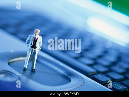 Small toy figure on computer keyboard, focus on figure, close-up Stock Photo
