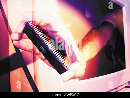Hand emerging from computer monitor, holding circuit board, digital composite. Stock Photo