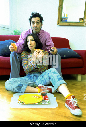 Man sitting on sofa, woman sitting on floor between man's legs. Stock Photo