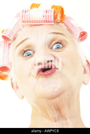 Elderly woman puckering lips and wearing hair rollers, portrait, close-up Stock Photo