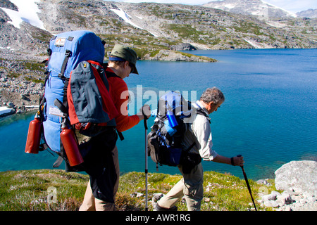 Hikers carrying backpacks at Crater Lake, mountain landscape, Chilkoot Trail, British Columbia, Canada Stock Photo