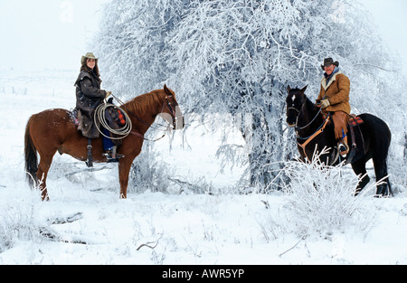 Cowboy and cowgirl surveying from horses, Canada Stock Photo