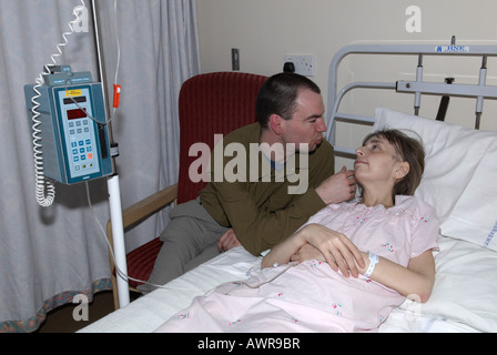 Partner (husband) comforting patient with a warm touch whilst patient is on a chemotherapy drip Stock Photo