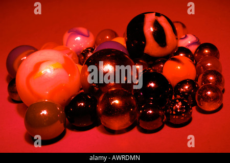 a group collection of childrens marbles on against a red background Stock Photo