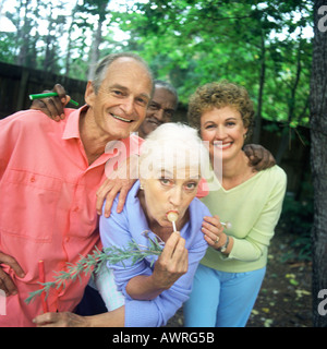 Four people standing outdoors, woman sucking lollipop Stock Photo