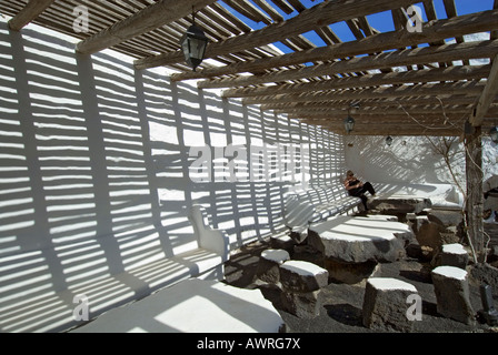 LANZAROTE RUSTIC SHADE VACATION RESTAURANT VOLCANIC LAVA TABLES Woman relaxes and reads in shaded terrace pergola, Lanzarote Canary Islands Spain Stock Photo