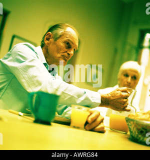 Mature couple sitting at table, man holding pitcher Stock Photo