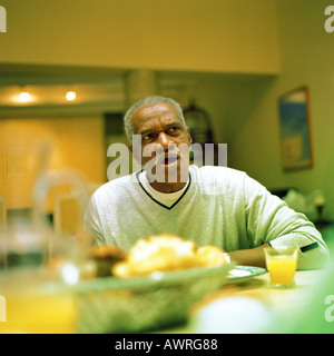 Mature man sitting at table Stock Photo