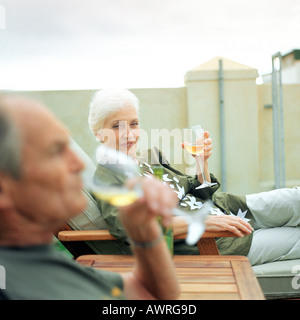 Mature man and woman having a drink outside, focus on woman in background Stock Photo