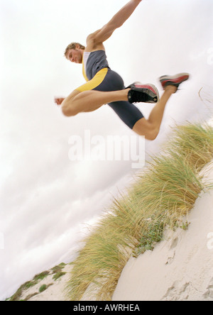 Young man on beach jumping, mid-air, low angle view. Stock Photo