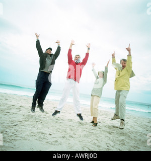 Mature group on beach, jumping in air, looking into camera Stock Photo