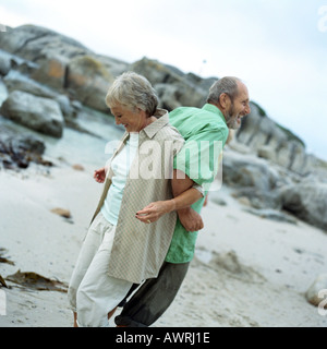 Mature couple standing back to back, arms locked, side view Stock Photo