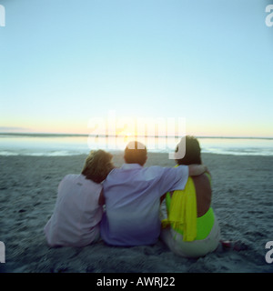 Mature friends sitting on beach,  rear view Stock Photo