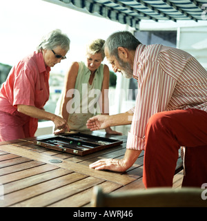 Three mature friends playing backgammon Stock Photo