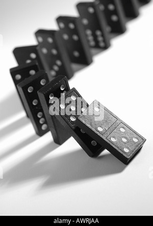 Lined up dominoes, beginning to fall Stock Photo