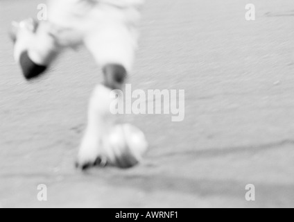 Soccer player kicking ball, blurred, b&w. Stock Photo