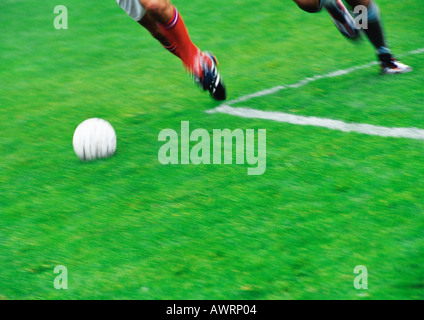 Two soccer players running for ball, blurred, low section. Stock Photo