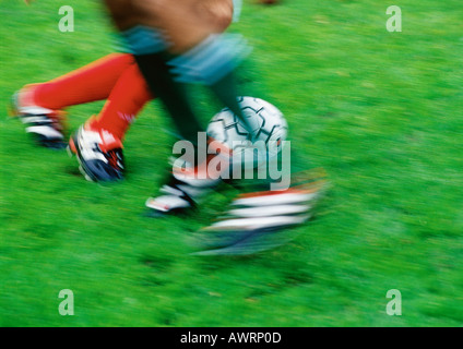 Two soccer players running for ball, low section, blurred. Stock Photo