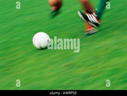 Feet of two soccer players running for ball, low section, blurred Stock Photo