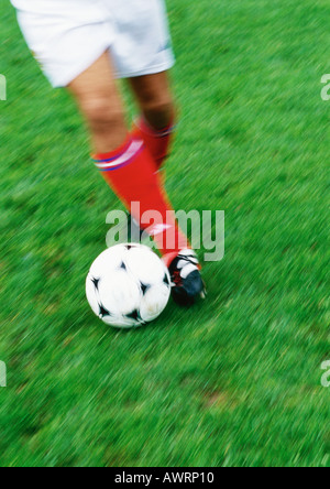 Soccer player running with ball, blurred, low section. Stock Photo