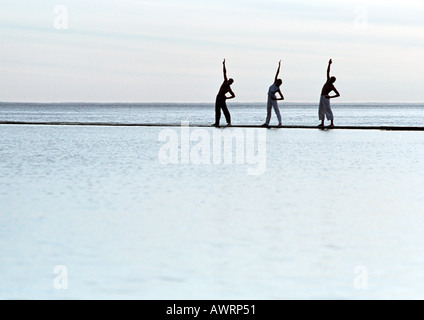 Three people exercising by the sea Stock Photo