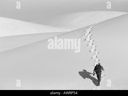 Man hiking up sand dune, rear view, b&w Stock Photo