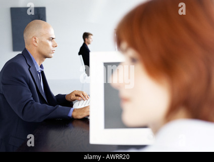People working in office, businessman using computer, side view Stock Photo