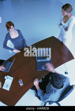 Business people around desk, two with laptops, elevated view Stock Photo