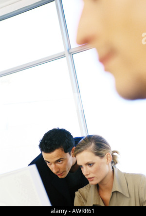 People working in office, man and woman looking at computer Stock Photo