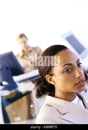 Businesswomen in office, one using cell phone, second using computer Stock Photo