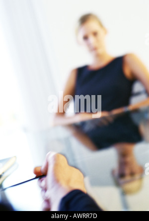 Businesswoman sitting at table, man's hand in foreground Stock Photo