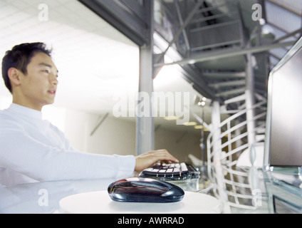 Man working on computer, side view, focus on mouse in foreground Stock Photo