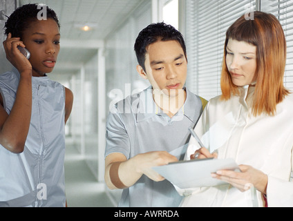 People in hallway, woman using cell phone, waist up Stock Photo