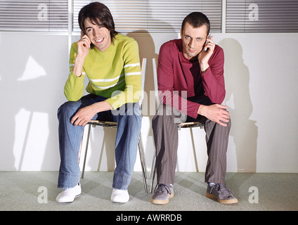 Two men in seats with cell phones Stock Photo