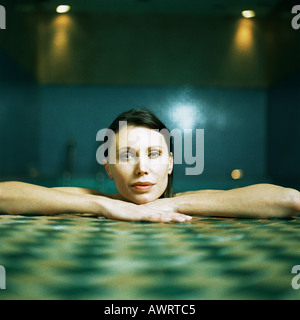 Woman resting arms and head on side of pool, portrait Stock Photo