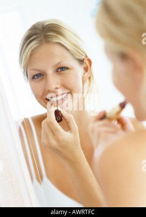 Woman putting on lipstick in mirror, portrait Stock Photo