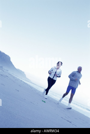 Mature man and woman running on beach Stock Photo