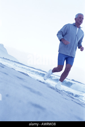 Mature man running on beach Stock Photo