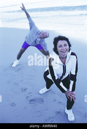 Mature man and woman stretching on beach Stock Photo