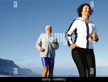 Mature couple running outdoors, low angle view Stock Photo