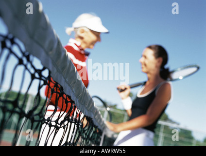 Two mature women talking on tennis court, blurred Stock Photo