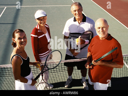 Four mature tennis players on court, portrait Stock Photo