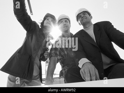 Two men and woman wearing hard hats, low angle view, b&w Stock Photo