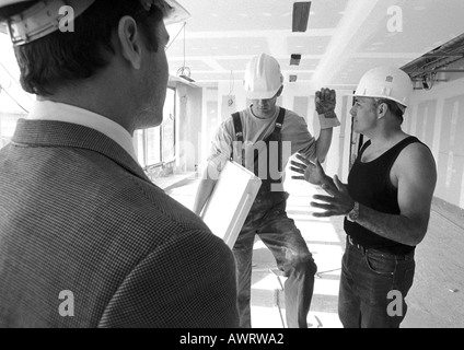 Men wearing hard hats, talking, b&w Stock Photo