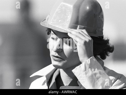 Woman holding hard hat, close-up, b&w Stock Photo