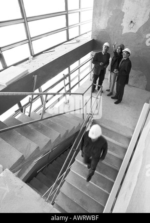 Four people on stairs, wearing hard hats, b&w Stock Photo
