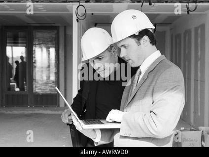 Two men with hard hats, one holding laptop computer, b&w Stock Photo