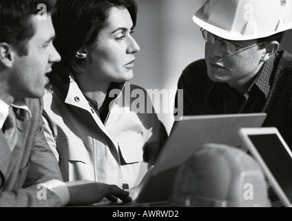Three people with laptop computer, one with hard hat, head and shoulders, b&w Stock Photo